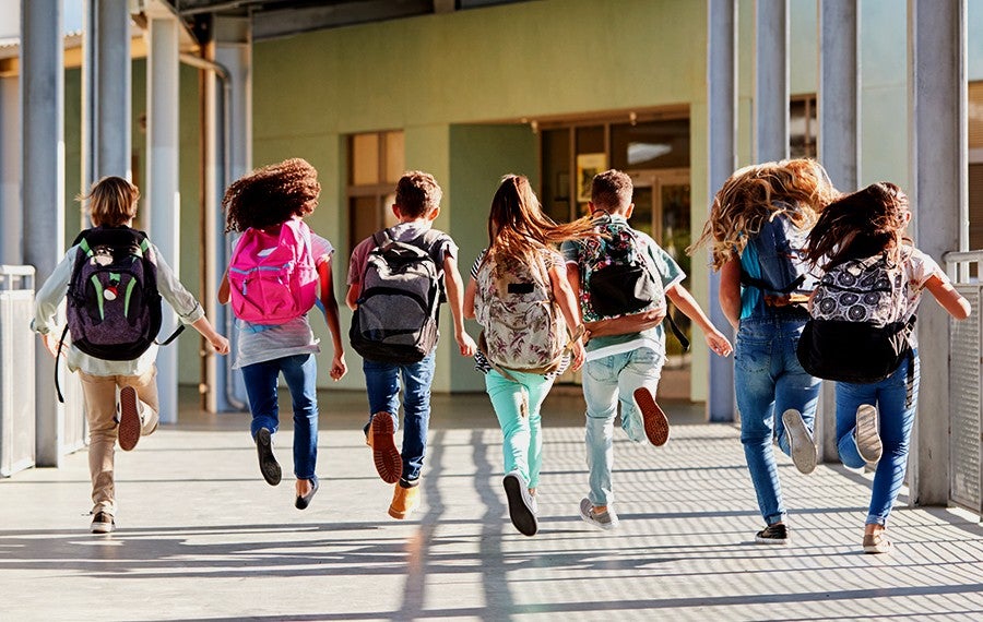 group of happy children skipping down school breezeway