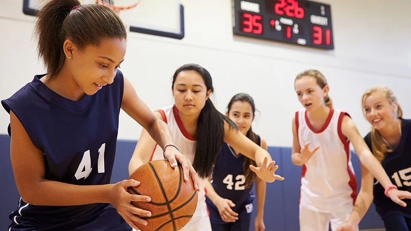 five young people playing basketball