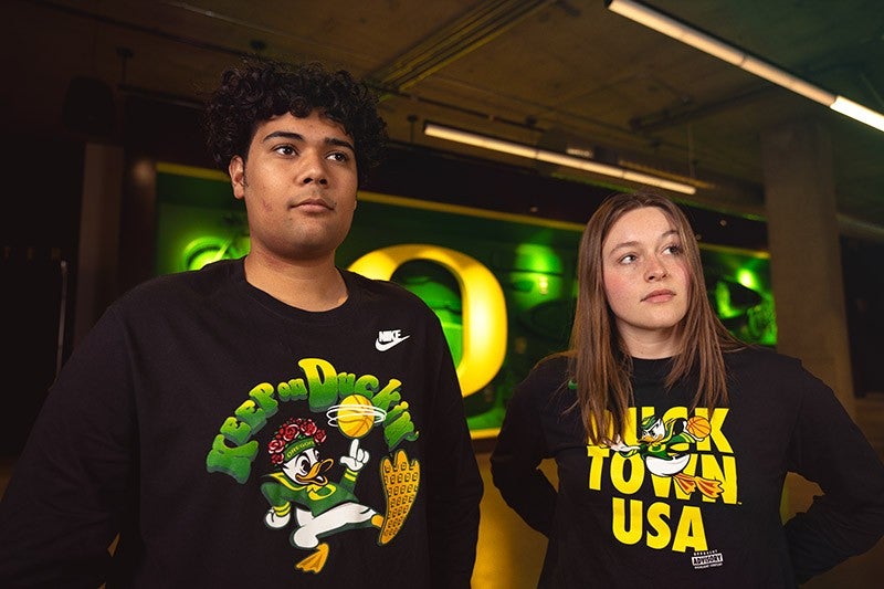 two people wearing UO shirts with the words "Keep on Duckin'" and"Track Town USA"