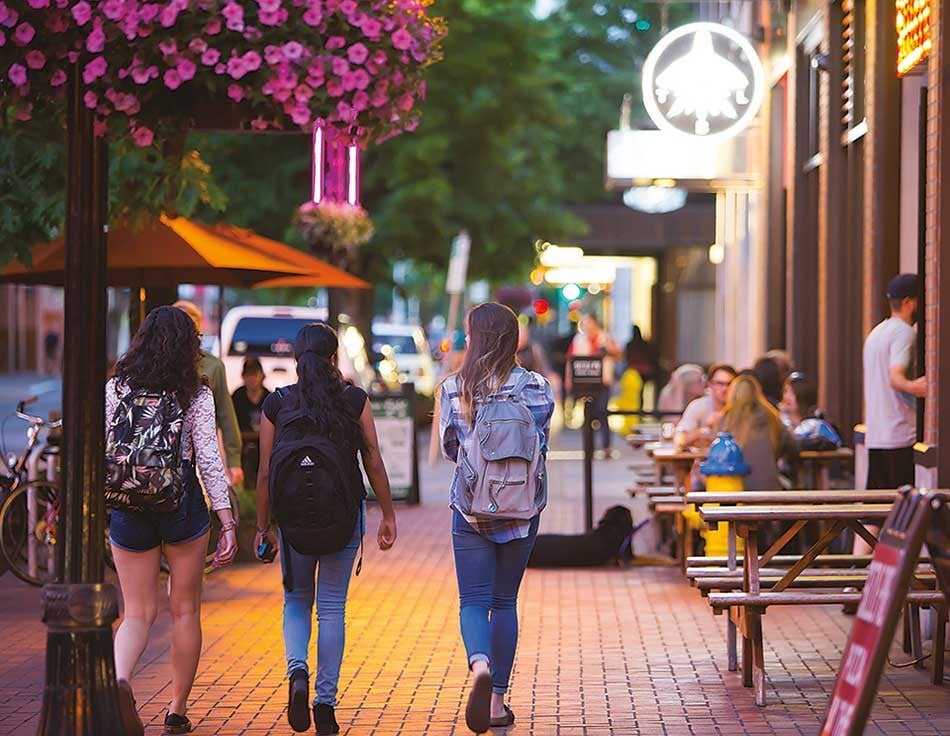 People walking down the sidewalk next to some shops in downtown Eugene