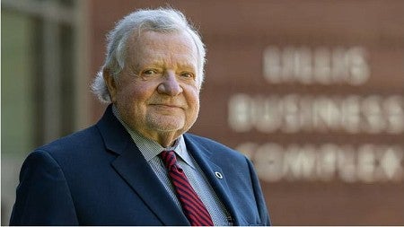 Portrait photo of Chuck Lillis standing outside the Lillis Business Complex on the UO campus