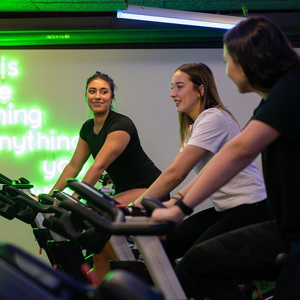 three female students on the stationery bikes